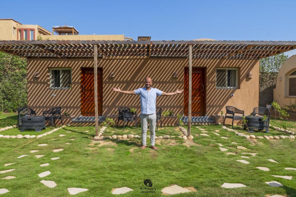 a man standing in a yard in front of a house at Sahure Pyramid View Inn in Cairo