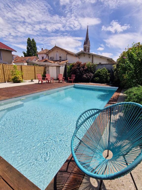 a blue rattan chair sitting next to a swimming pool at Maison plein centre - Piscine in Mimizan