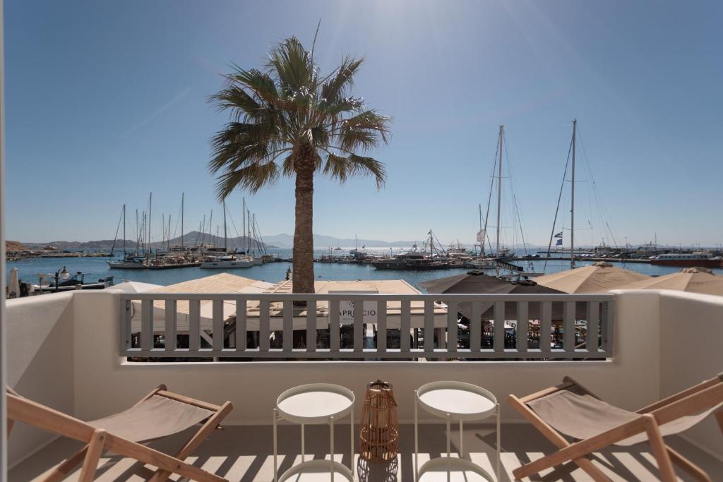 a balcony with chairs and a palm tree and a marina at Casa di Grazia in Naxos Chora