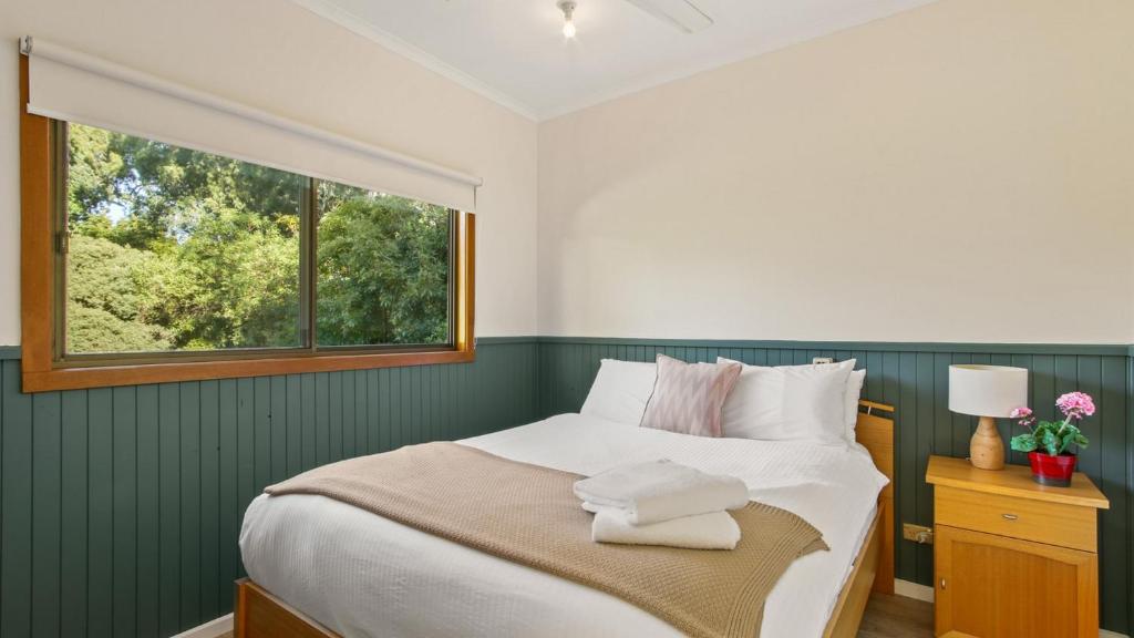a bedroom with a large bed with a window at Treetop Retreat Cottage in Metung