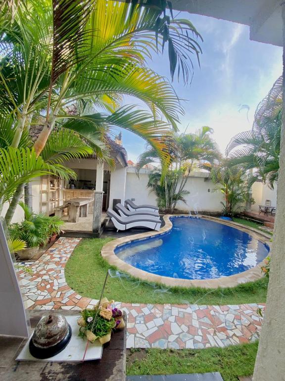 a swimming pool in a yard with palm trees at Mango 5 Hotel in Amed