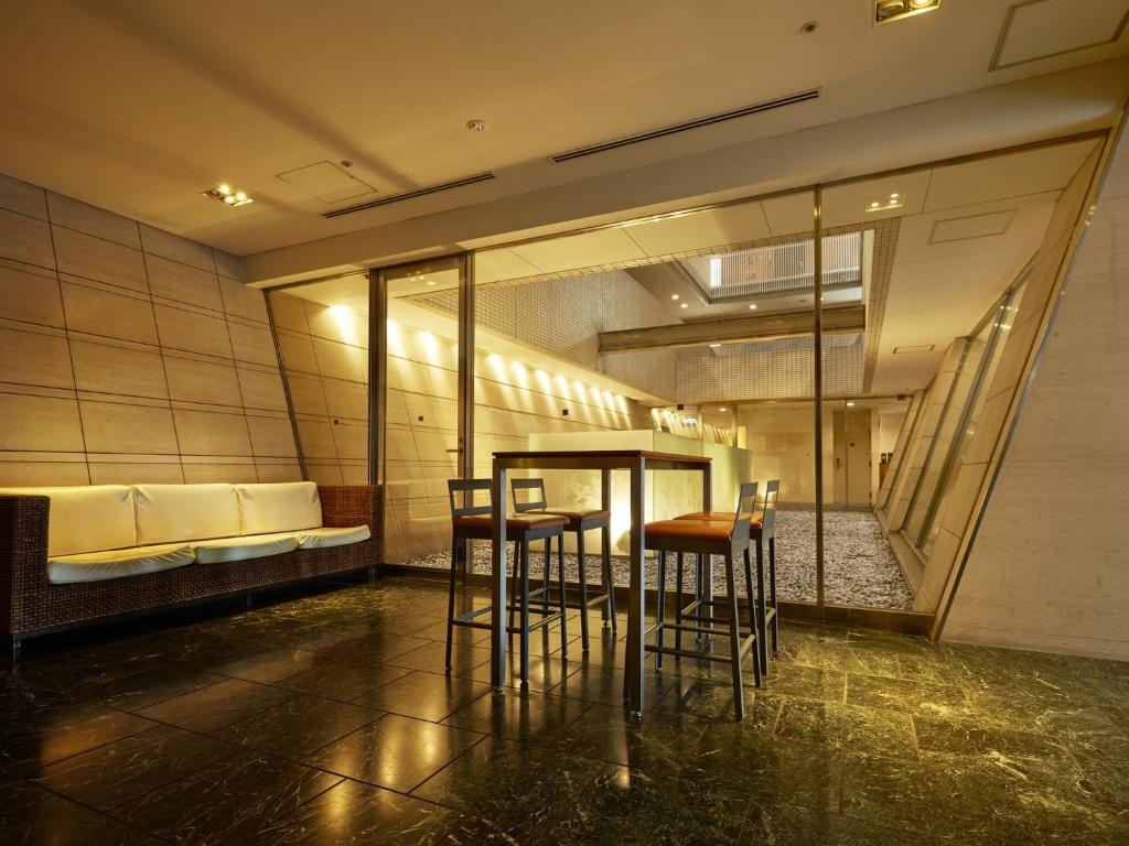 a room with a table and chairs and a couch at Hotel Villa Fontaine Tokyo-Ueno Okachimachi in Tokyo