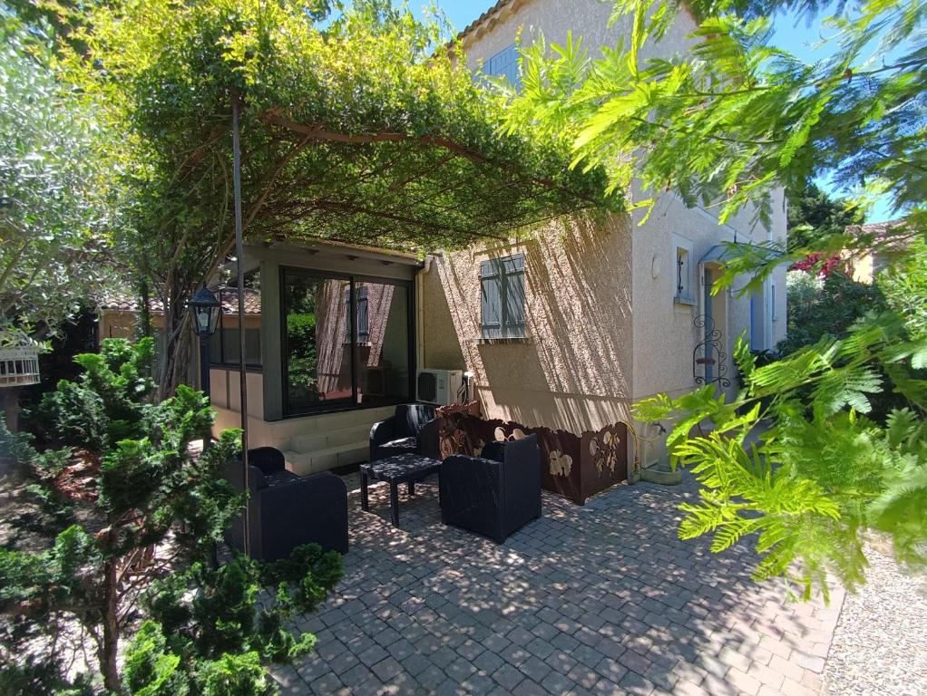 un patio d'une maison avec des chaises et des arbres dans l'établissement Maison provençale avec piscine partagée, à Loriol-du-Comtat