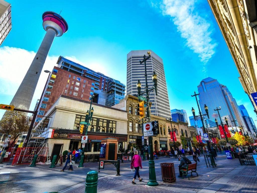 a city street with people crossing a street with a tower at A Spacious Downtown 1-bed Suite in Calgary