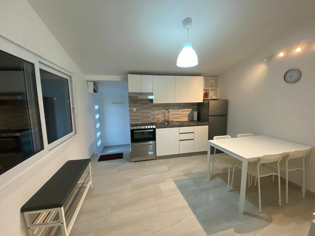 a kitchen with a white table and a table and chairs at Apartmani Gršćica 2 in Blato