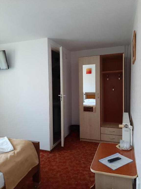 a hotel room with a bed and a table and a door at Pensiunea Sanlex in Bicaz