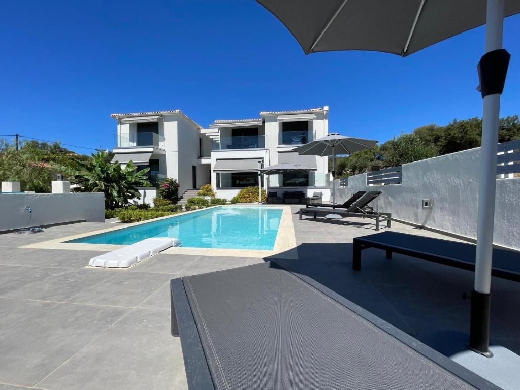 a swimming pool with an umbrella and a house at Magic Kefalonia Villa in Spartia