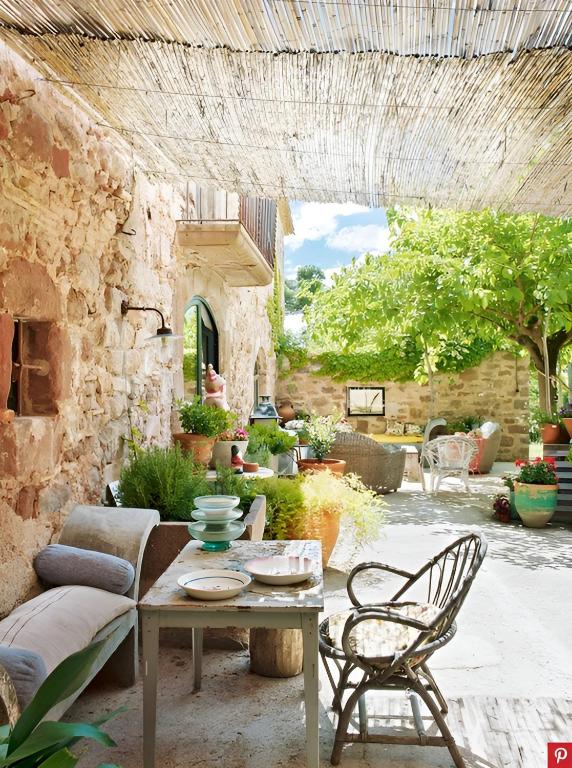a patio with a table and chairs and a stone wall at Masia Vilatersana in Sant Llorenc Savall