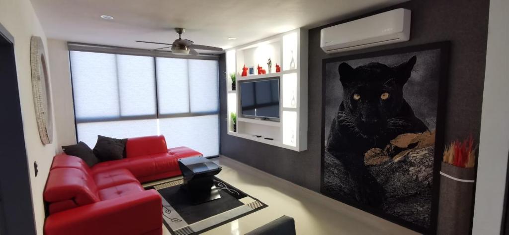 ein Wohnzimmer mit einem roten Sofa und einem Gemälde in der Unterkunft Hermoso departamento para vacacionar in Mazatlán