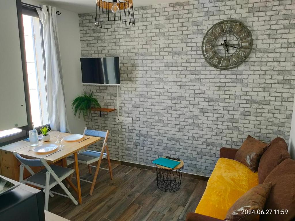 - un salon avec une table et un mur en briques dans l'établissement Charmant et cosy 200m de port, à La Ciotat