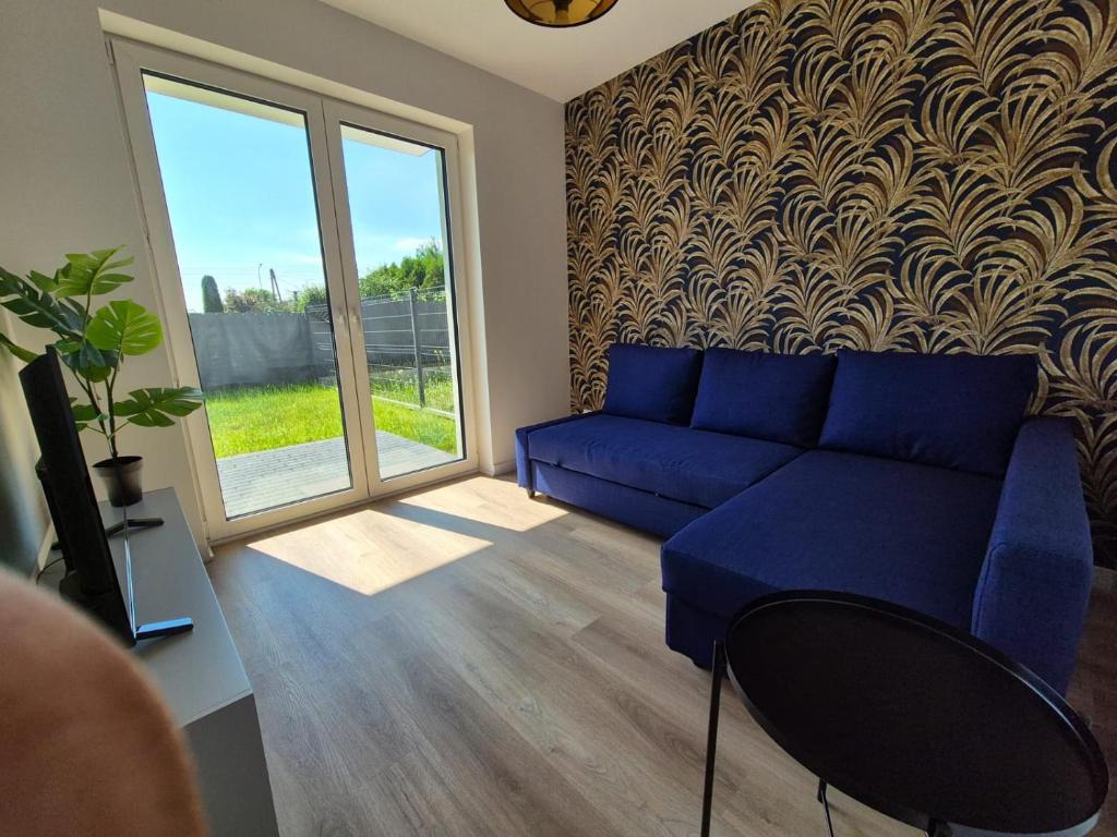 un salon avec un canapé bleu et une fenêtre dans l'établissement Apartament Sportowa przy SUNTAGO DEEPSPOT Mszczonów, à Mszczonów