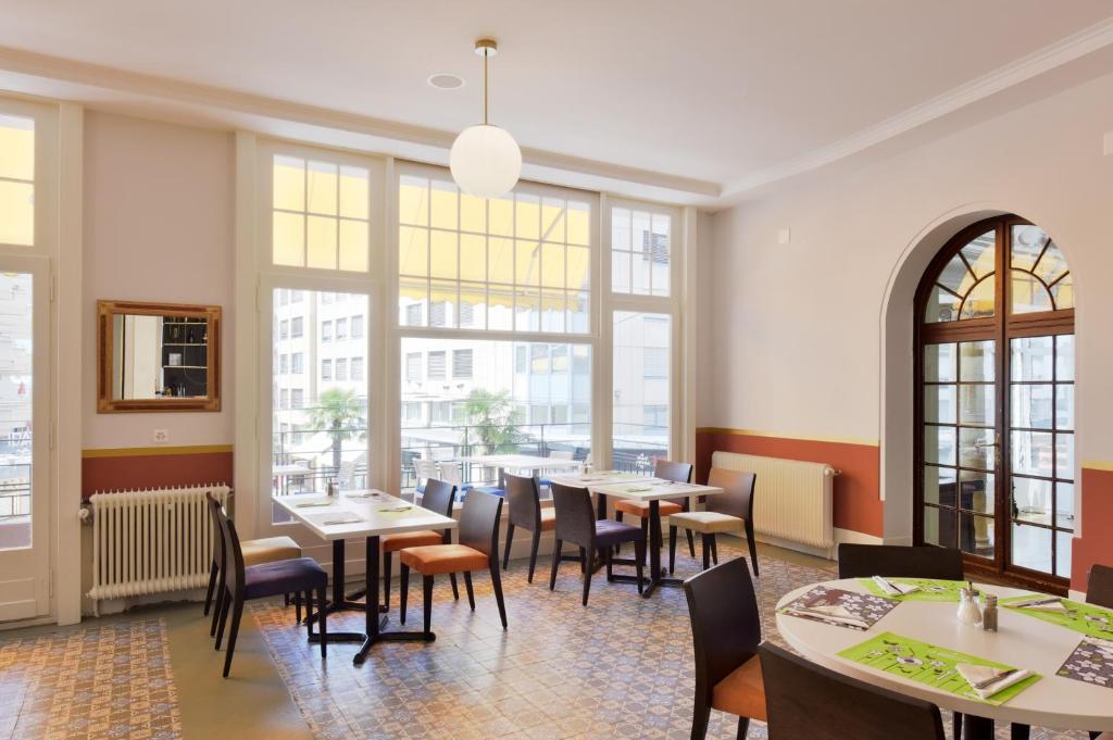 a restaurant with tables and chairs and large windows at J5 Hotels Helvetie & La Brasserie in Montreux