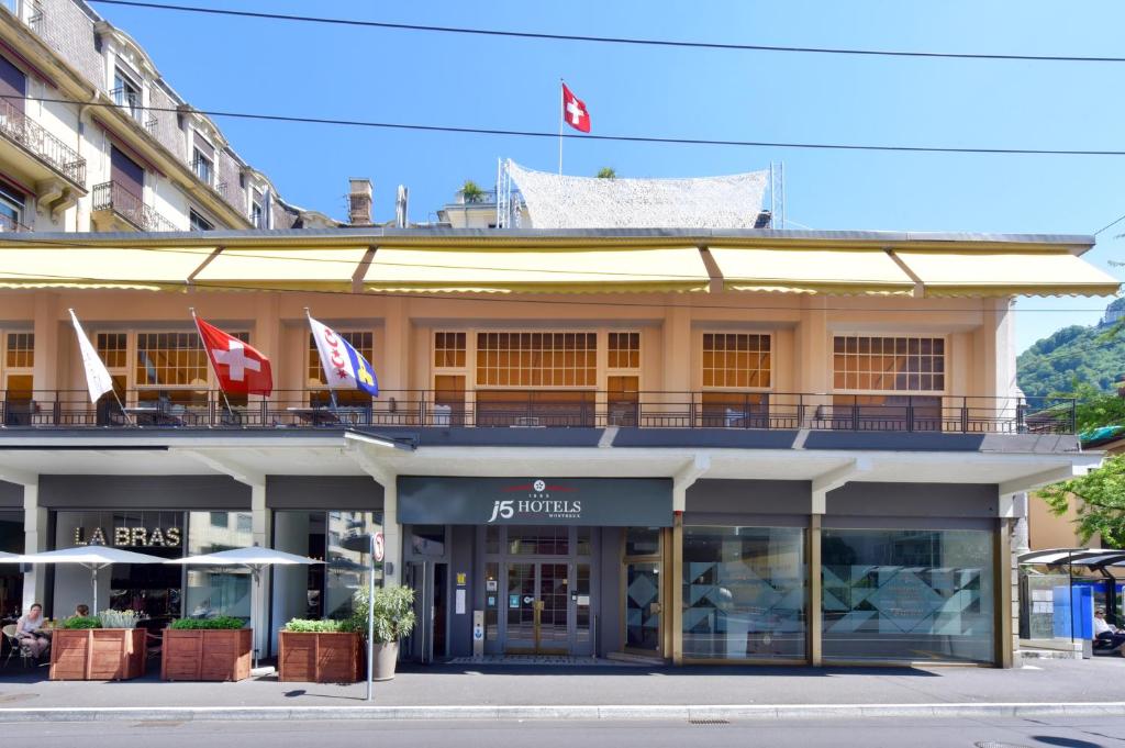 a building with flags on top of it on a street at J5 Hotels Helvetie & La Brasserie in Montreux