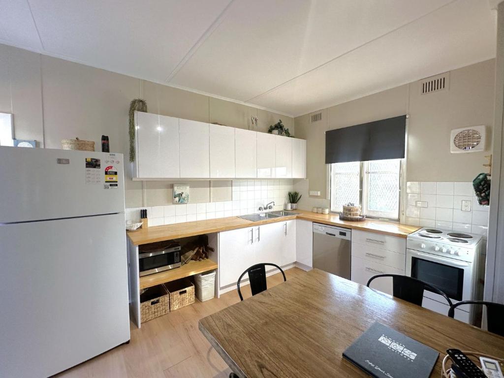 a kitchen with a table and a white refrigerator at Exmouth Villas Unit 29 in Exmouth