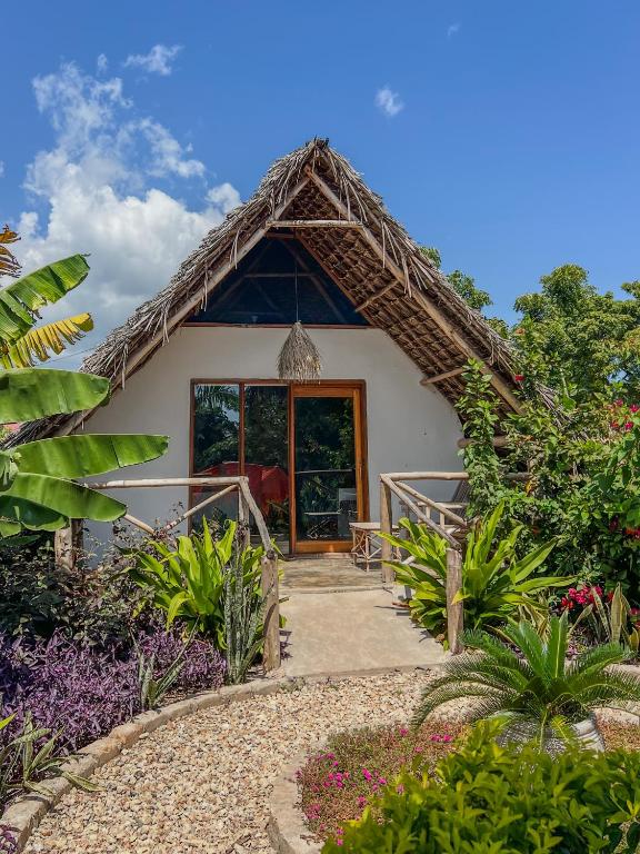 a small house with a thatched roof at Kokopelli Bungalows in Nungwi