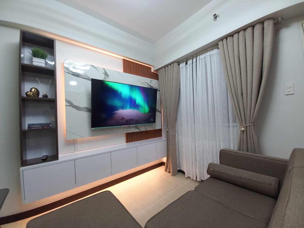 a living room with a flat screen tv on a wall at Comfy 2 Bedroom Condominium at Verdon Parc Ecoland in Davao City