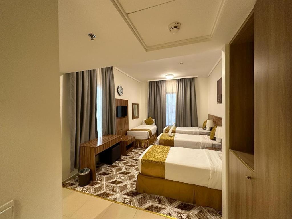 a hotel room with two beds and a living room at Sama Al Amany Hotel in Makkah
