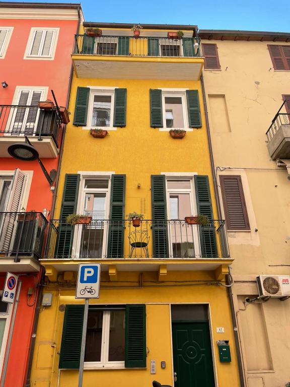 un edificio giallo con persiane verdi e un cartello di parcheggio di La Scala a Chiocciola a San Benedetto del Tronto