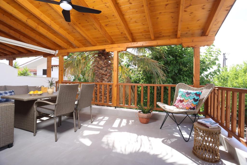 eine Terrasse mit einer Holzterrasse mit Stühlen und einem Tisch in der Unterkunft Blue Sand Apartment in Pefkohori