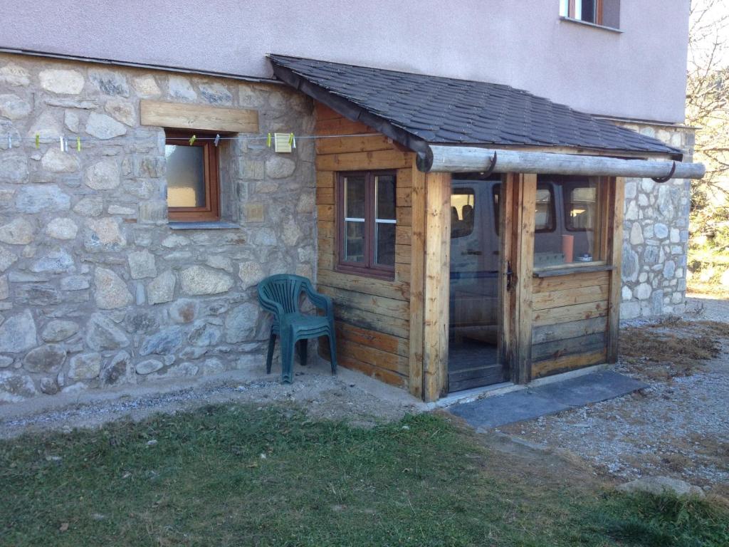a wooden shed with a chair next to a building at Appartement paisible près des pistes de ski 4 pers in Fontrabiouse