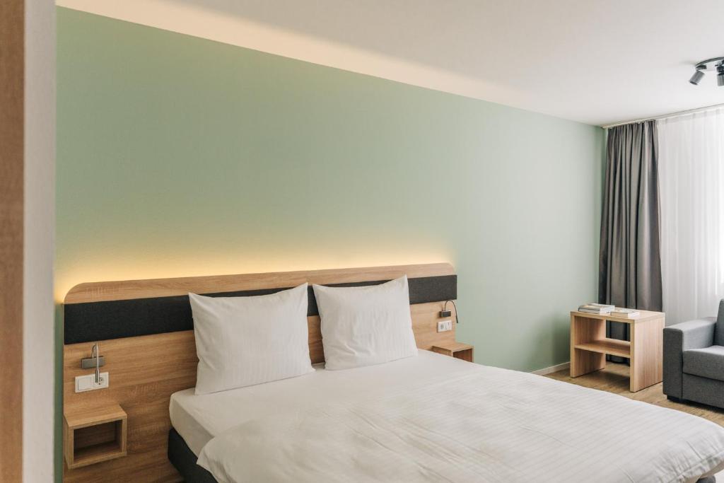 a hotel room with a bed and a chair at Homaris Corner Hotel in Frankfurt/Main