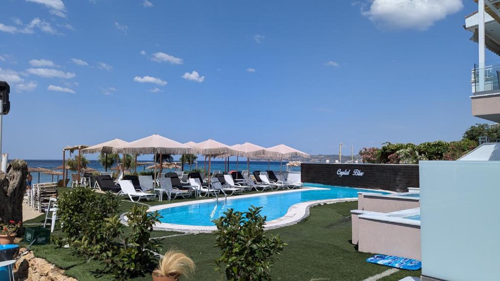 a woman standing next to a swimming pool with chairs and umbrellas at Crystal Blue in Potos
