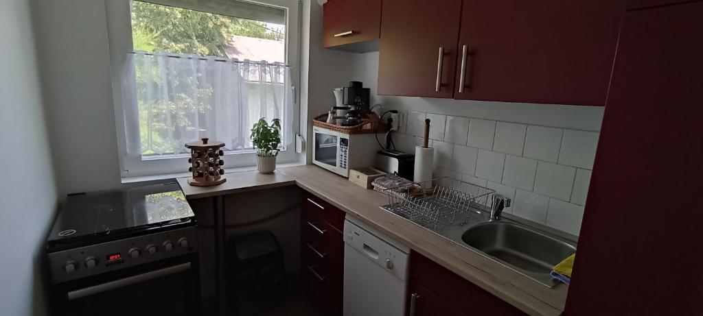kuchnia ze zlewem, kuchenką i oknem w obiekcie Krezo Ház w Gyenesdiás