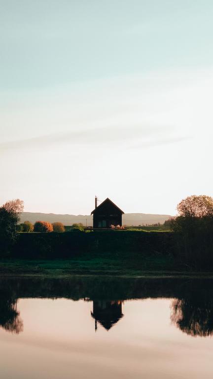 a barn sitting on top of a field next to a lake at Stabburet Madam Meyer in Skage i Namdalen