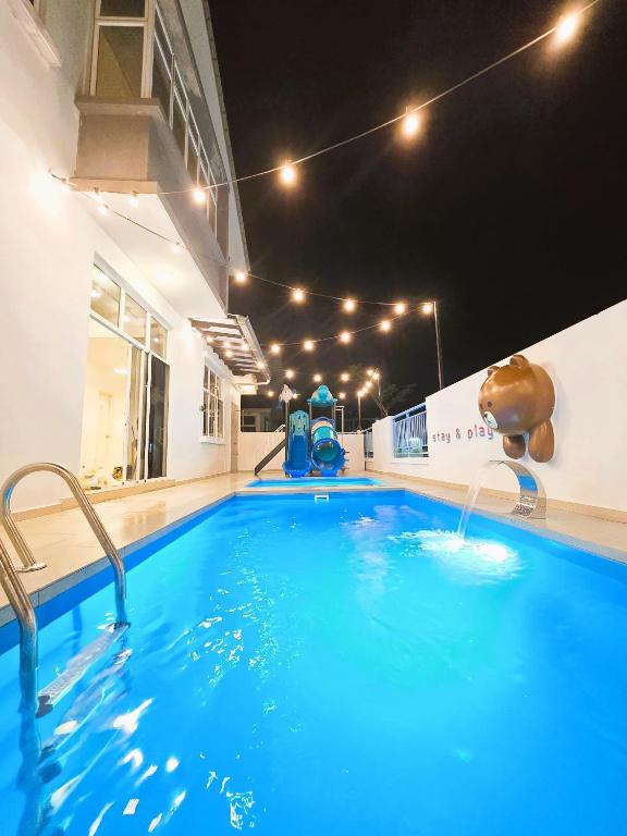 a large swimming pool with blue water in a building at Desaru Kids Water Slide Private Pool & BBQ Homestay Bandar Penawar in Bandar Penawar