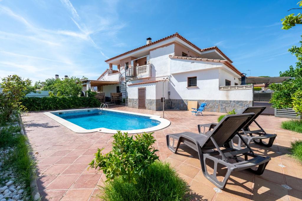 a villa with a swimming pool and two chairs at La Plana in Creixell