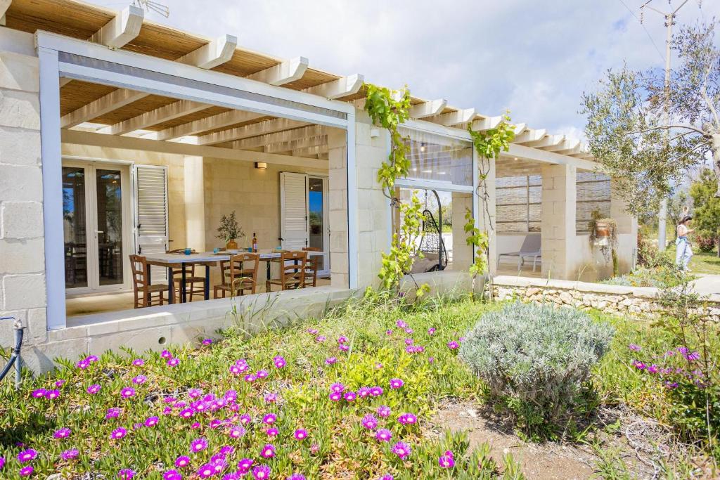a house with a patio with a table and flowers at Villa La Reimunda in Otranto