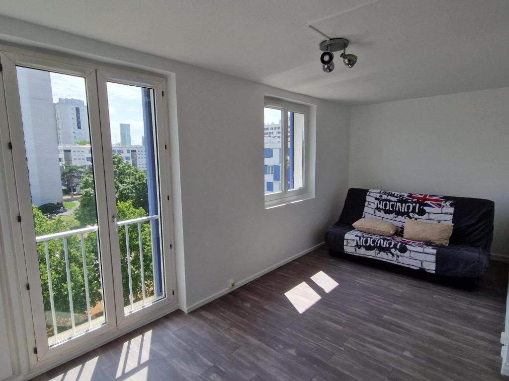 - un salon avec un canapé et de grandes fenêtres dans l'établissement Location Studio meublé période Jeux Olympiques, à Rosny-sous-Bois