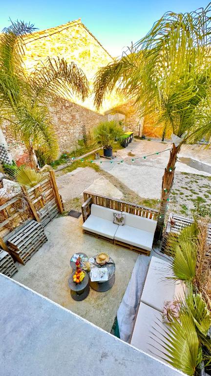 un patio avec un banc blanc et des palmiers dans l'établissement Les Gîtes de la Chapelle 3, à Vauvert