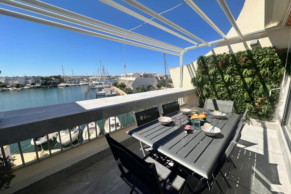 une table sur un balcon avec vue sur l'eau dans l'établissement Le Plaisancier - Appartement Terrasse Vue sur le Port de Plaisance parking, au Grau-du-Roi