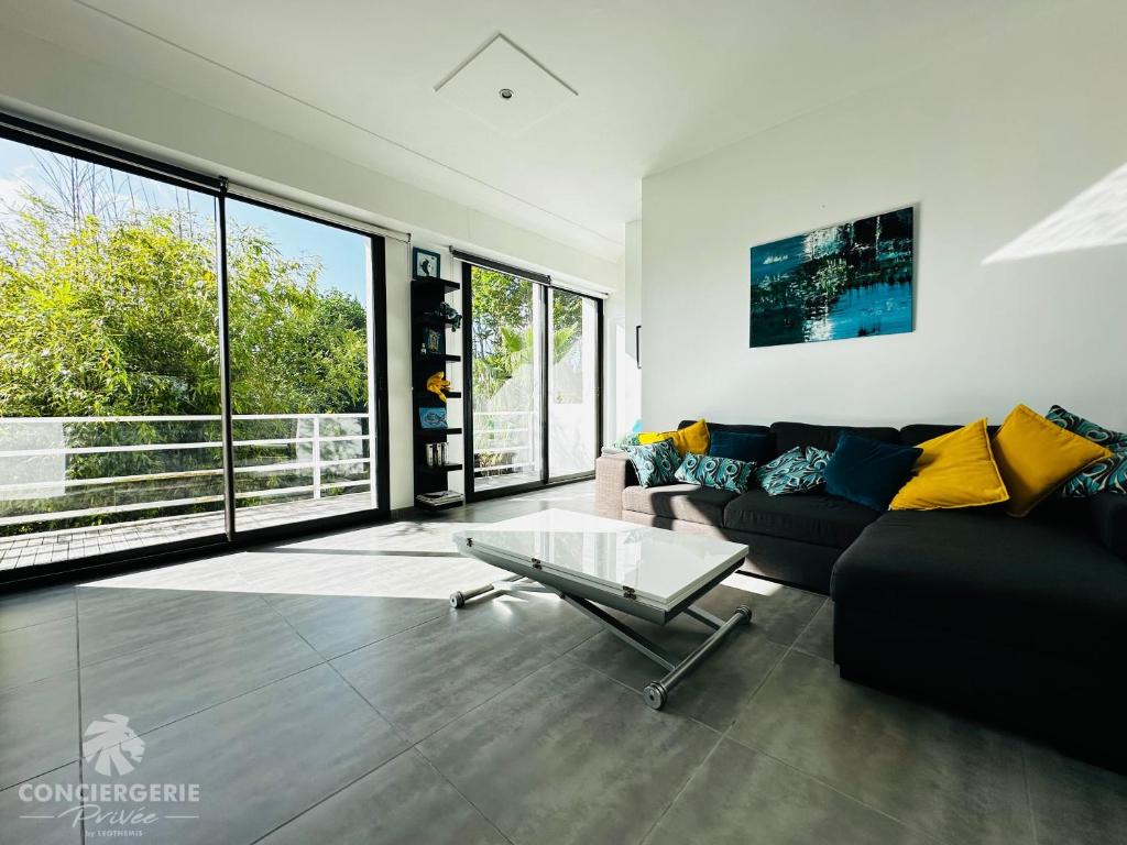 - un salon avec un canapé noir et une table en verre dans l'établissement Appartement lumineux et moderne - Le Tropical, à Royan