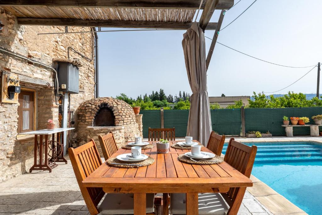 a wooden table on a patio next to a pool at Lo Molí de la Jòrdia in Tortosa