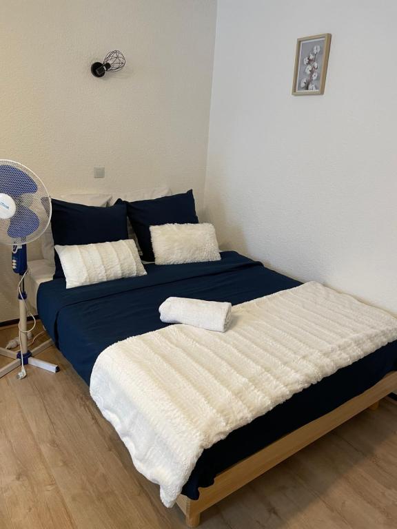 - une chambre avec un lit doté de draps bleus et blancs et d'un ventilateur dans l'établissement Cocon de Zoé, à Nancy