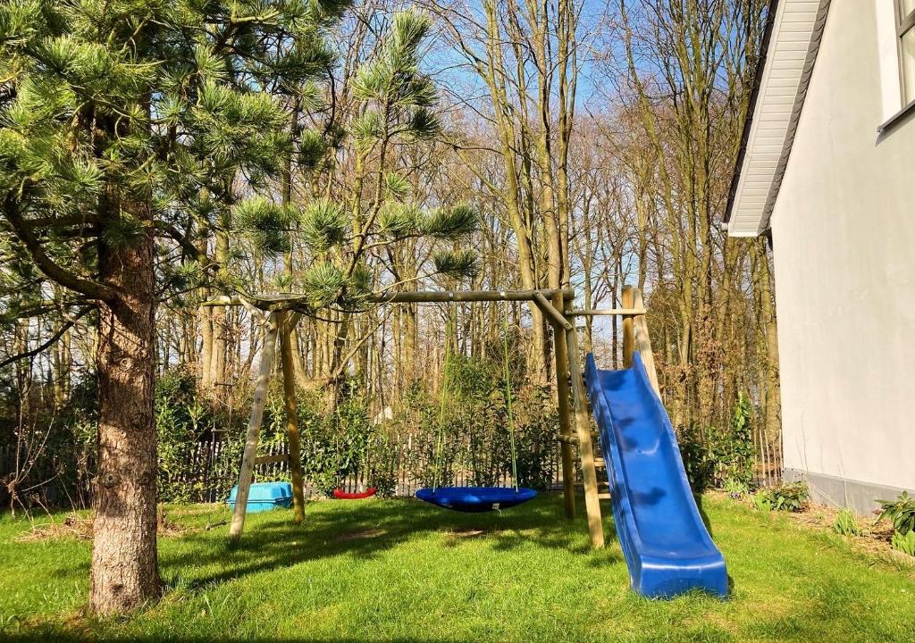una diapositiva azul en un patio junto a un árbol en Ferienhaus Visselheide, en Visselhövede
