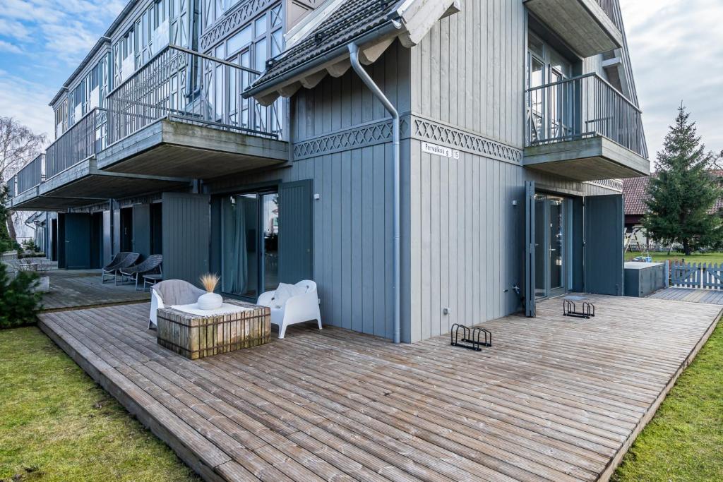 a house with a wooden deck in front of it at Marių Veranda in Pervalka