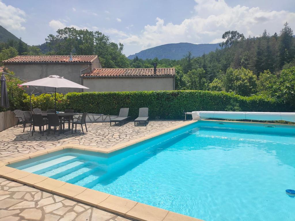 une piscine avec une table, des chaises et un parasol dans l'établissement Coste de Laval, à Quillan