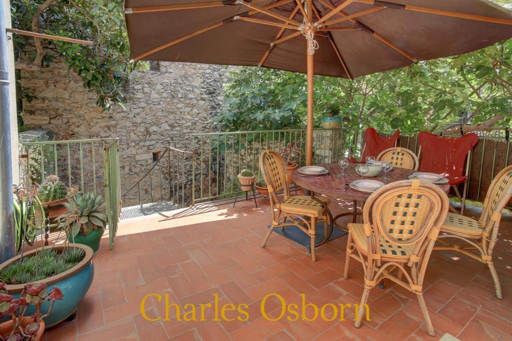 un patio avec une table, des chaises et un parasol dans l'établissement La Havanaise - jardin et terrasse, à Sète
