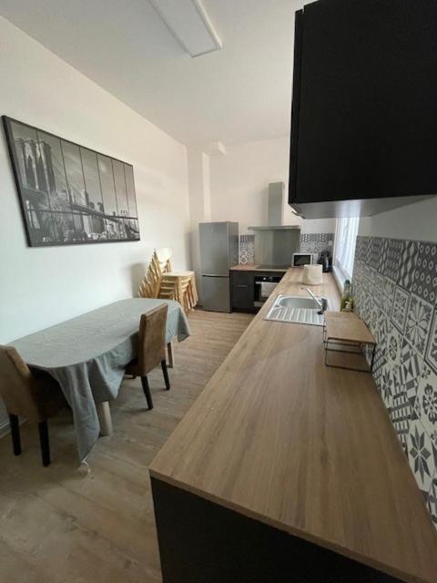 un salon avec une table et une cuisine dans l'établissement La Léonce, superbe appartement plein centre, à Armentières