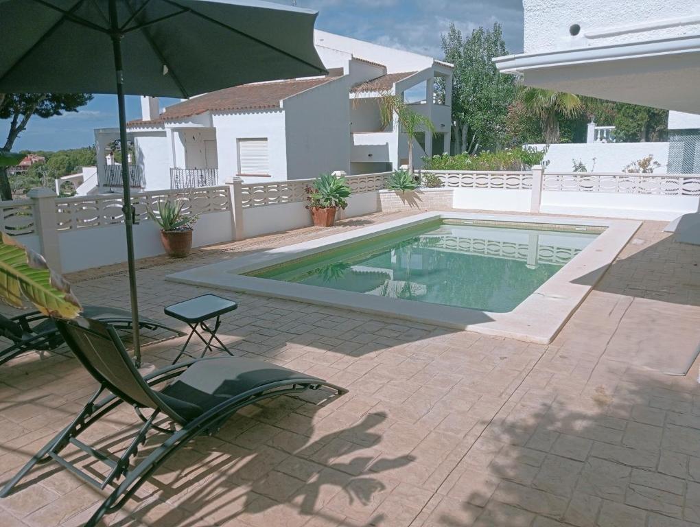 a chair and an umbrella next to a swimming pool at AT Chalet Stella con Piscina Privada in Peniscola