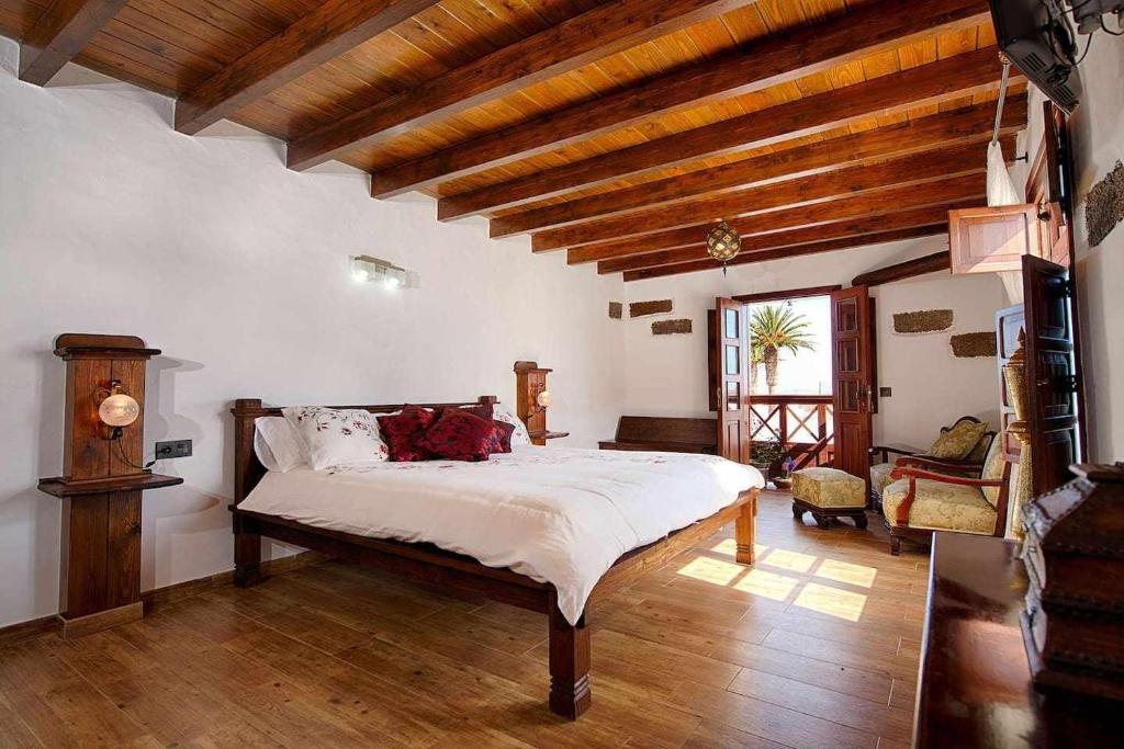 a bedroom with a large bed in a room with wooden ceilings at Casa Emblemática Garaday Lanzarote. in Tinajo