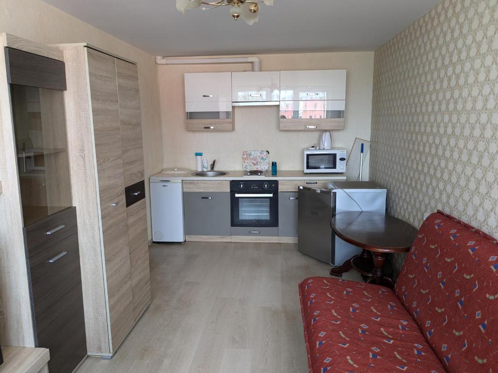 una pequeña cocina con un sofá rojo en una habitación en Комната в общежитии блочного типа, en Klaipėda