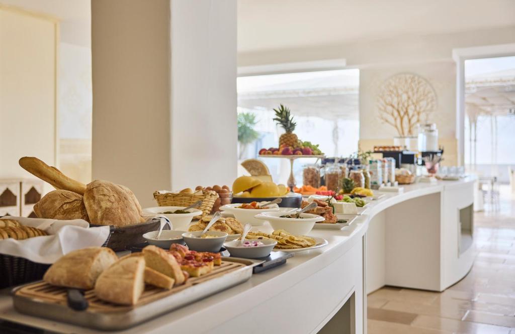 a breakfast buffet with bread and pastries on a counter at La Casa E Il Mare, Private Bay Hotel in Mattinata