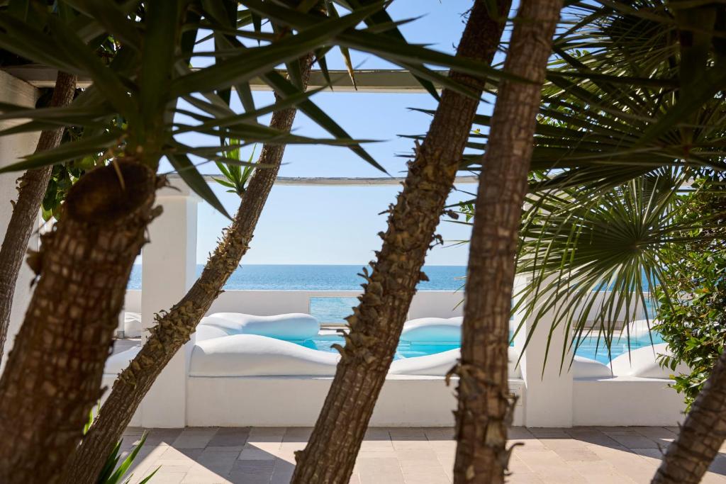 a view of the ocean through the palm trees at La Casa E Il Mare, Private Bay Hotel in Mattinata