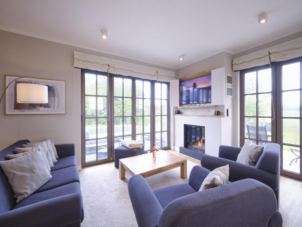 a living room with blue couches and a fireplace at Reetland am Meer - LuxusPlus Reetdachvilla mit 4 Schlafzimmern, Außensauna, Loungebereich und Kamin H05 in Dranske