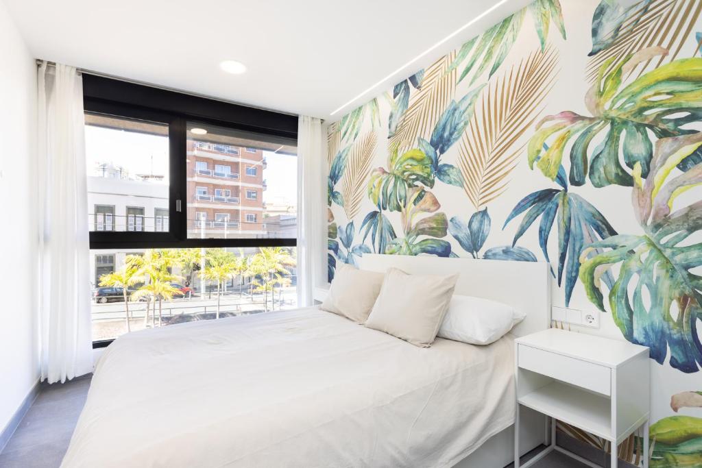a bedroom with a white bed with a tropical mural at Home2Book Design & Spacious Apartment City Center in Santa Cruz de Tenerife