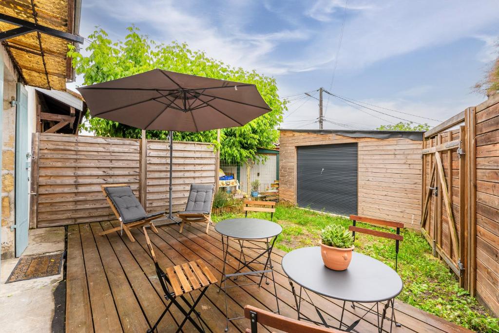 un patio avec une table, des chaises et un parasol dans l'établissement La Listracaise - Charmante maison pour 5 voyageurs, à Listrac-Médoc